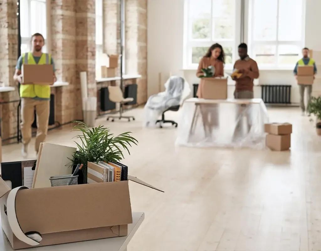 Umzugsteam trägt Kartons durch ein helles Büro